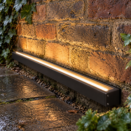 Outdoor linear LED wall washer throwing light up a wet British brick garden wall