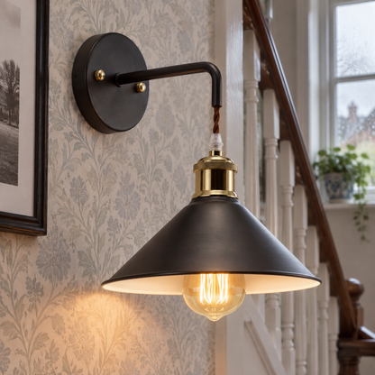 Industrial oil-rubbed bronze metal wall sconce on a wall in a British hallway