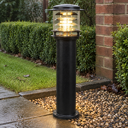 Modern garden bollard light lighting a gravel path in a damp British garden