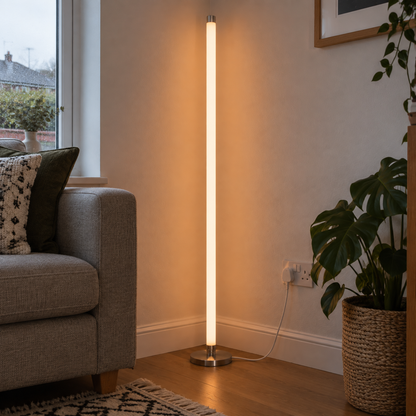 Slim linear LED neon tube floor lamp lit beside a sofa on a patterned wool rug
