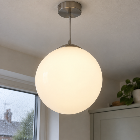 Large opal glass globe pendant light hanging in a kitchen on a grey rainy afternoon