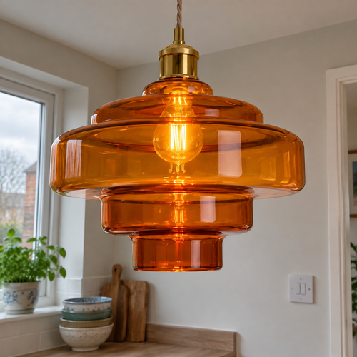 Orange macaron glass pendant light glowing above a kitchen breakfast bar