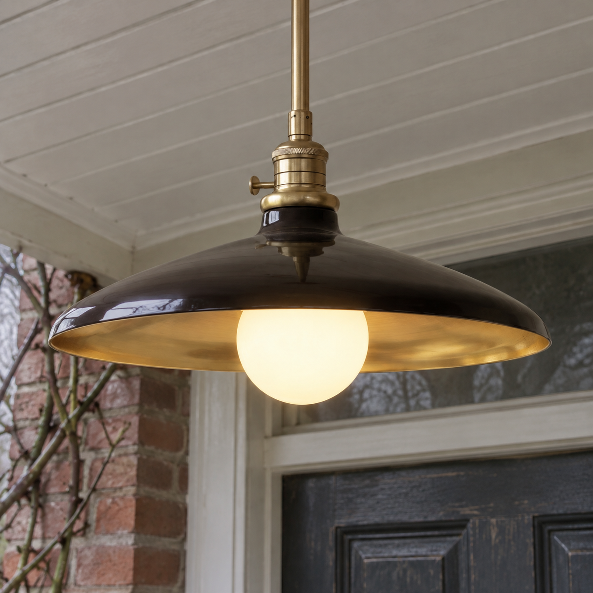 Metal and clear glass outdoor lantern pendant hanging lit in a porch on a misty day