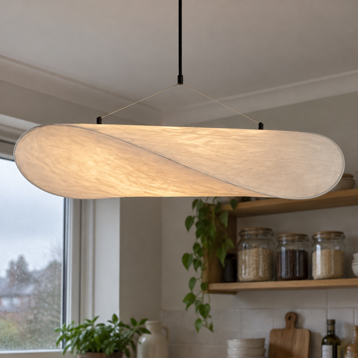 Minimalist paper pendant light glowing above a kitchen worktop on an overcast morning