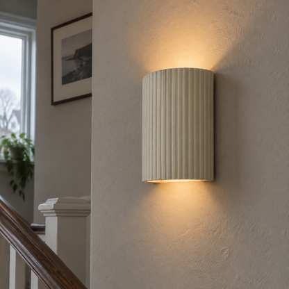 Scandinavian beige plaster semicircle wall sconce washing light up a stairwell wall