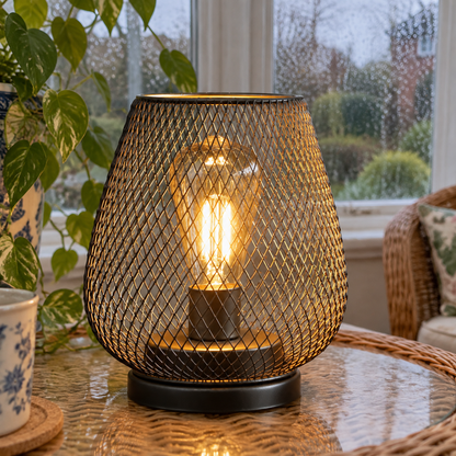 Cordless rechargeable portable table lamp switched on and standing upright on a conservatory side table