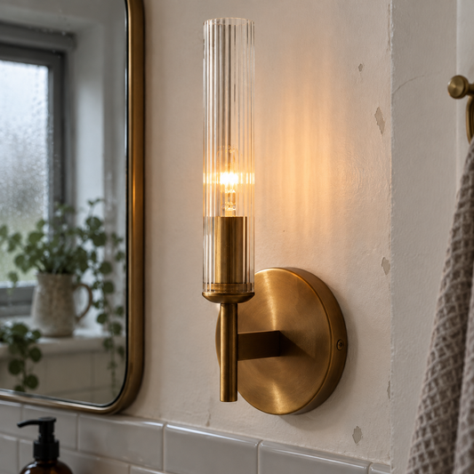 Copper farmhouse ribbed glass tube sconce lit beside a bathroom mirror