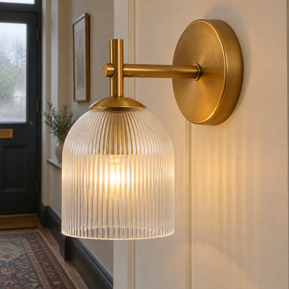 Copper ribbed glass wall sconce lit on a panelled hallway wall above a worn runner rug in a British home