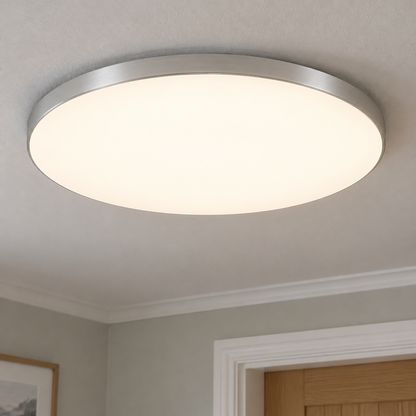 Round minimalist LED flush ceiling light fitted flat to a plain ceiling beside a picture rail