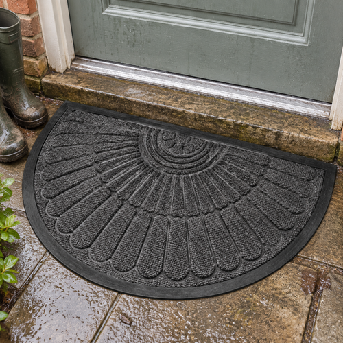 Semi-circular ribbed rubber door mat lying flat on a wet stone doorstep beside muddy wellingtons