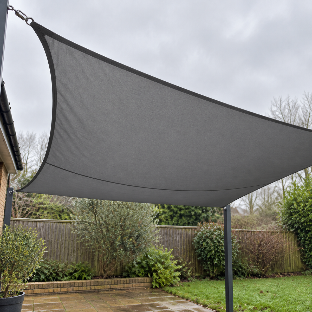 Outdoor shade sail canopy tensioned above a brick patio in a damp British garden