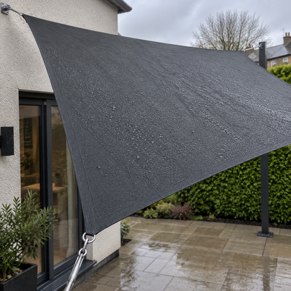Waterproof rectangular shade sail stretched taut over a wet patio on a grey blustery afternoon