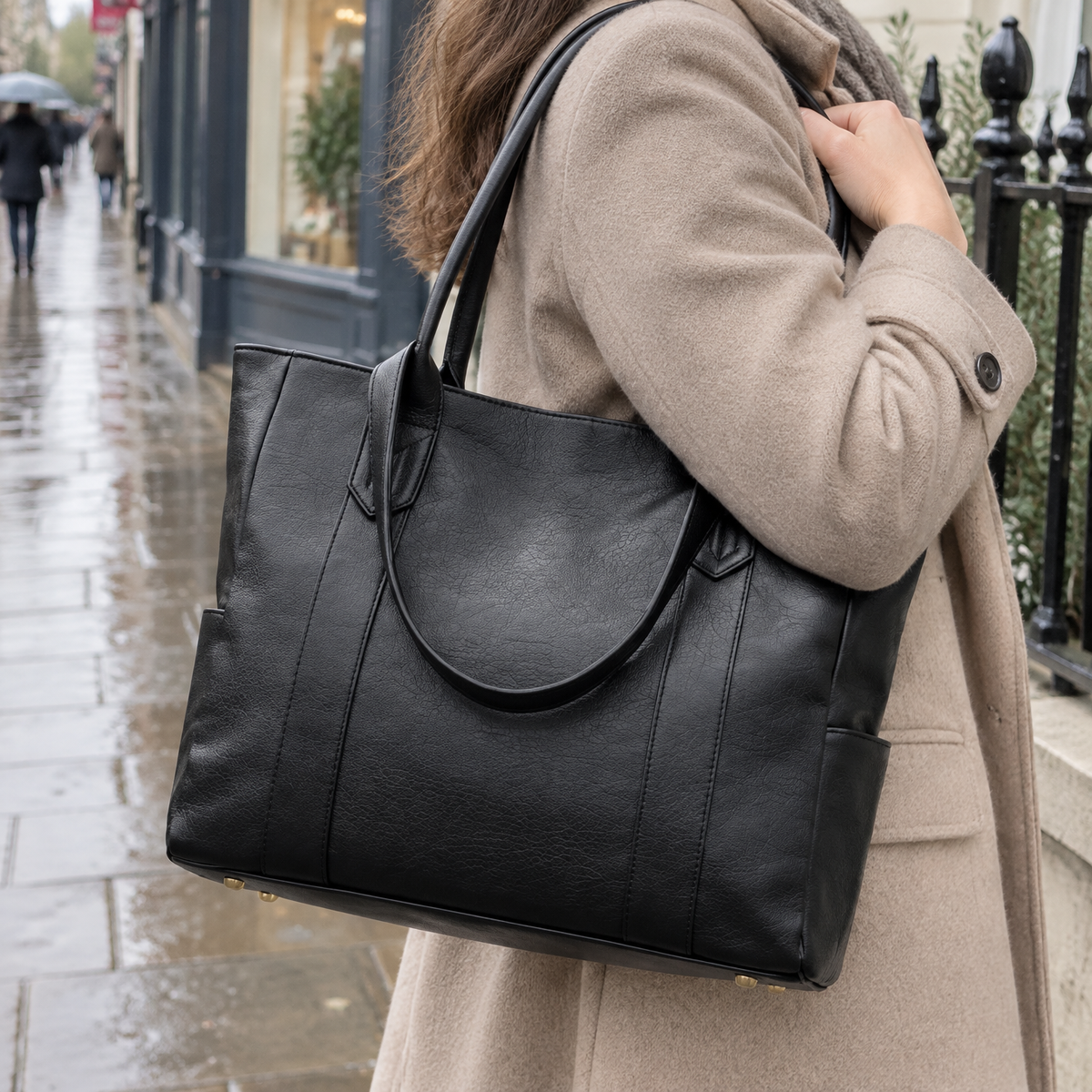 Woman carrying a leather-effect PU shoulder tote bag past iron railings on a drizzly afternoon