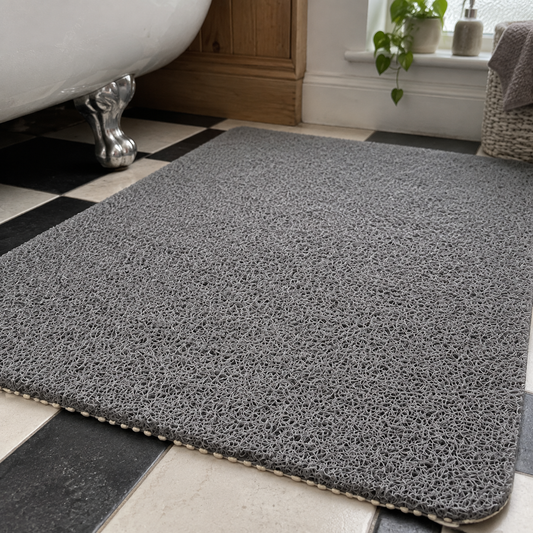 Soft cuttable non-slip bathroom mat laid flat on tiled floor beside a cast-iron bath