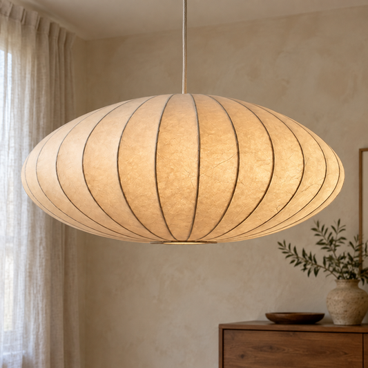 Silk wabi-sabi pendant light glowing above a low wooden dresser against a plastered wall