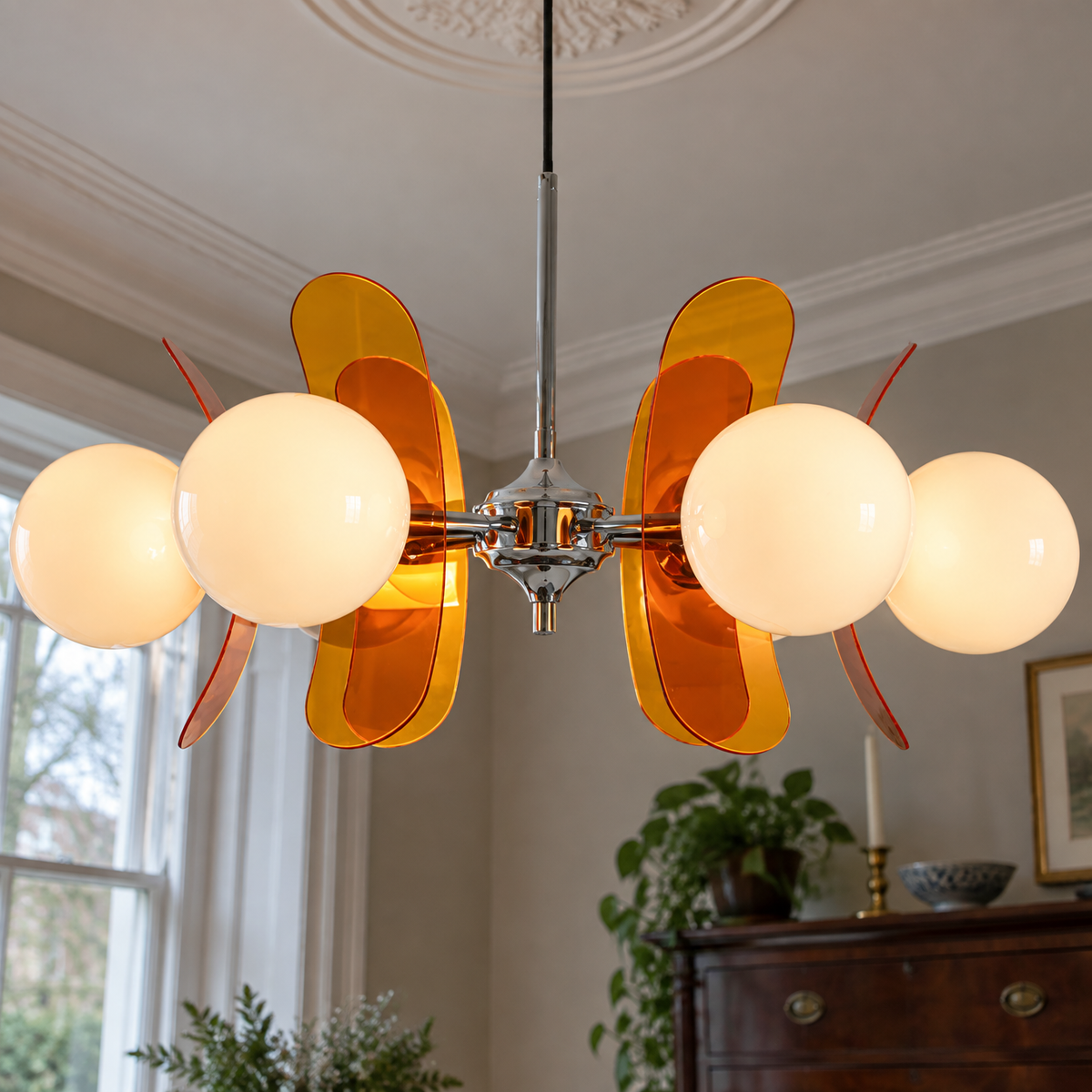 Brass sputnik chandelier with coloured glass globes hanging from a plaster ceiling rose in a dining room with a mahogany dresser behind