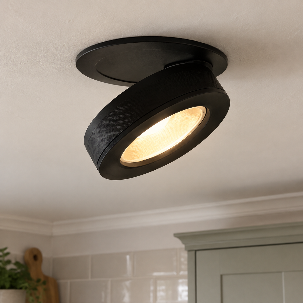Adjustable semi-recessed LED tilt downlight fitted into a kitchen ceiling, its inner reflector angled and switched on warm white