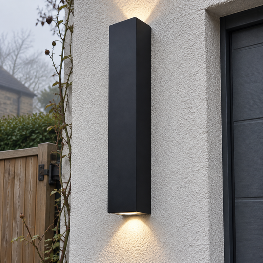Tall black rectangular up and down outdoor wall light fixed upright on a rendered garage wall on a misty morning