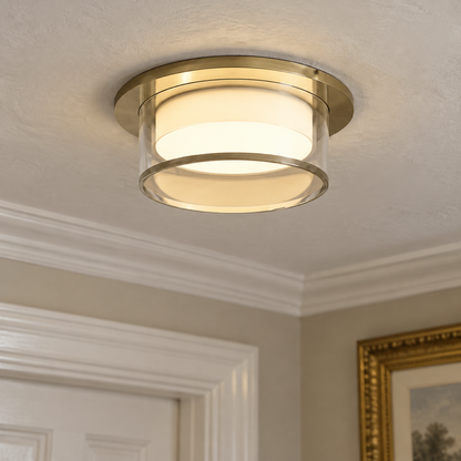 Decorative brushed gold semi-recessed downlight set into a hallway ceiling beside deep plaster cornicing