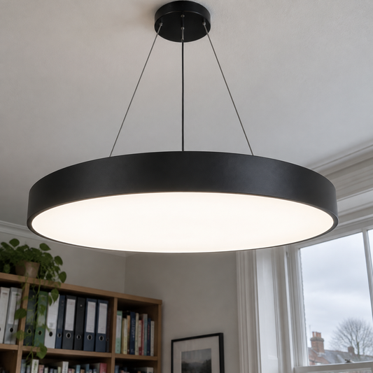 Black circular LED ring pendant hanging level above a home office desk, lit diffuser facing downward