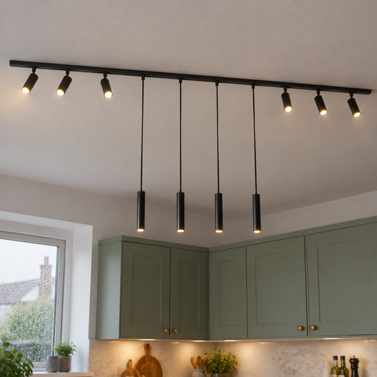 Black ceiling track carrying six adjustable spotlights and four hanging pendants above a sage green kitchen