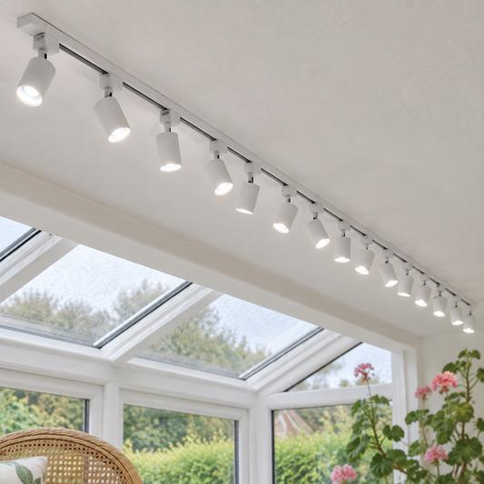 White single-phase track with fourteen white spotlights fixed to a conservatory ceiling beside a glazed roof beam