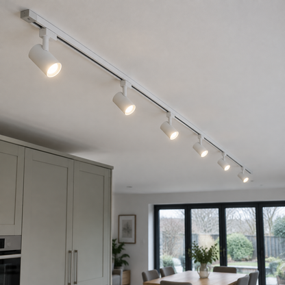 Long white ceiling track with six widely spaced white spotlights running through an open-plan kitchen-diner