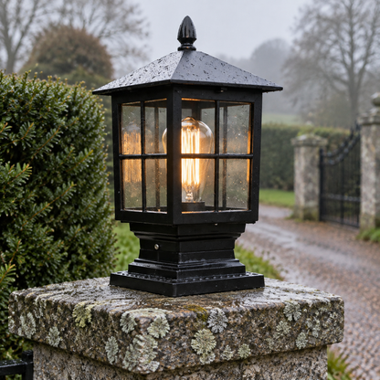 Traditional black aluminium and glass gate pillar lantern standing upright on lichen-spotted granite coping
