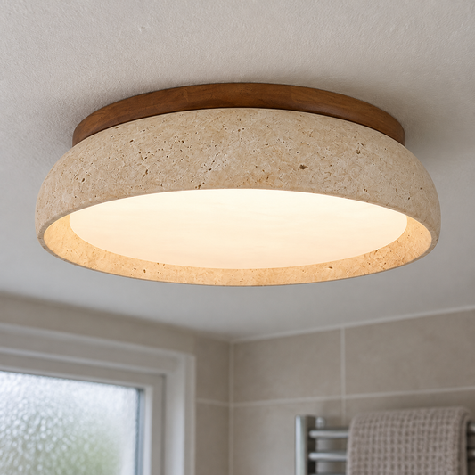 Round natural travertine LED flush mount fitted flat to a bathroom ceiling above a tiled wall and towel rail