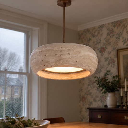 Wide travertine drum pendant light suspended over a dining table, creamy veined stone shade lit above a mahogany sideboard and floral wallpaper
