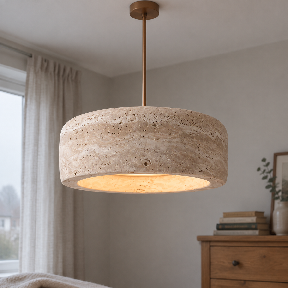 Cream travertine pendant light hanging in a bedroom, rounded vintage stone shade glowing softly above a wooden chest of drawers and books
