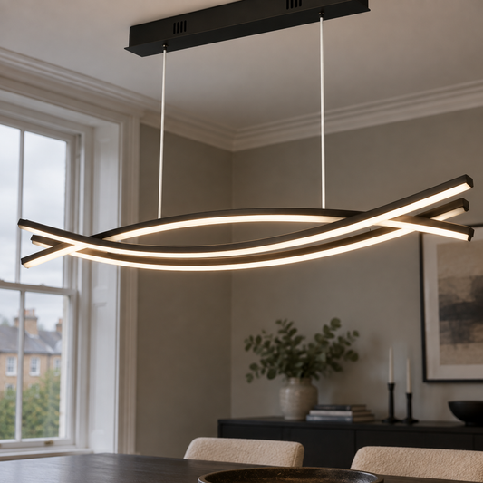 Curved wave linear pendant light hanging level above a dark dining table, sculptural aluminium bar casting a warm band of light