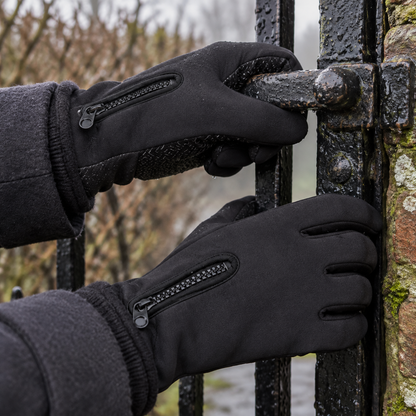 Waterproof thermal touchscreen winter gloves worn on a woman's hands gripping a wet metal garden gate latch