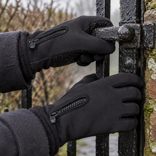 Waterproof thermal touchscreen winter gloves worn on a woman's hands gripping a wet metal garden gate latch