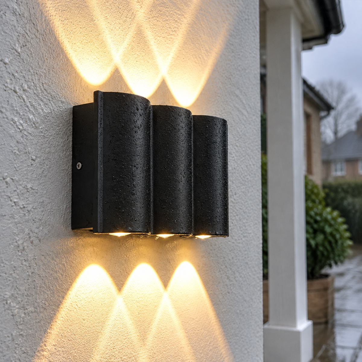 Wave design up and down outdoor wall light fixed to damp render beside a porch, warm beams above and below